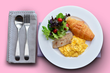 Breakfast set ( Scrambled egg, croissant and vietnamese pork sausage with black pepper) on pink background