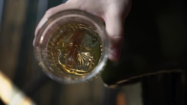 Man holding glass of whisky with ice closeup