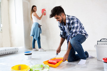 Man using take color with roller to painting house