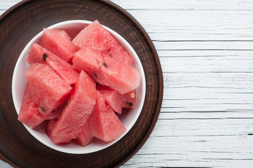 watermelon slices in plate on white wooden background top view