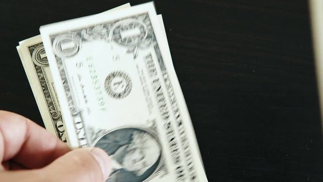 Close-up of a businessman's hands counting one dollar bills at a black table. Business stock footage shot. 