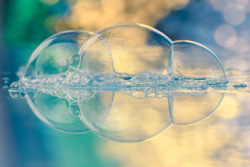 Drei Seifenblasen auf Glas mit buntem Hintergrund