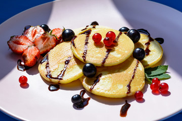 Ruddy pancake with berries in the bright rays of the morning sun.