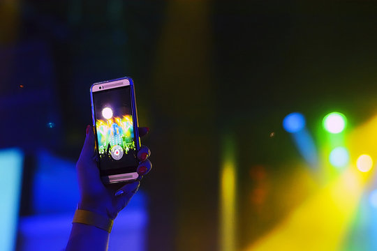 silhouette of hands with a smartphone at a concert