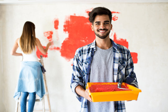Young couple decorate their new apartment.They painting new home