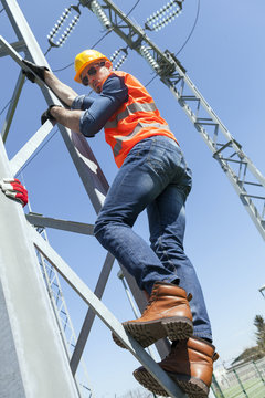 Engineer climbing electricity pylon
