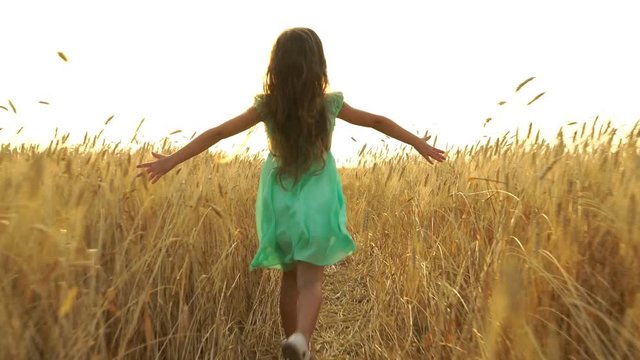 young girl in the dress is running across the field.