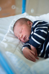 Newborn baby laying in crib in prenatal hospital