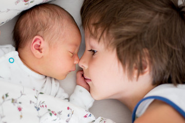 bBeautiful boy, hugging with tenderness and care his newborn baby brother at home