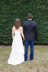 Back view of holding hands couple in love, bride and groom in french police uniform outdoor walking on field