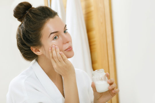 Woman Applying Coconut Oil On Her Face