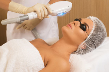 Beautiful woman in beauty salon during photo rejuvenation procedure - obrazy, fototapety, plakaty