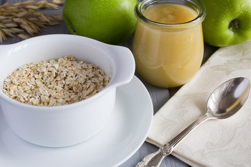 Breakfast with oat flakes and apples puree on the grey wooden background