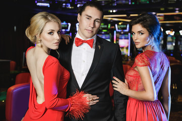 Confident man and two beautiful women in the casino