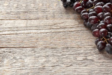 Ripe dark grapes with leaves, on wooden background. Selectiva focus. Copy space.