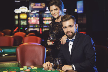 Beautiful and rich couple playing roulette in the casino