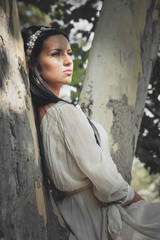 pretty young woman in romantic dress sit on tree in wood