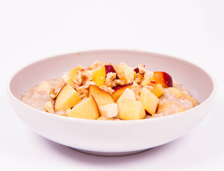 Porridge with peach, apple, banana and walnut on a white background