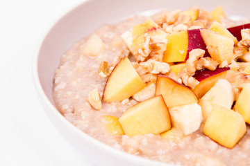 Porridge with peach, apple, banana and walnut on a white background