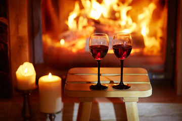 Two glasses of red wine near fireplace