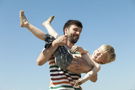 Father on beach fooling around with son