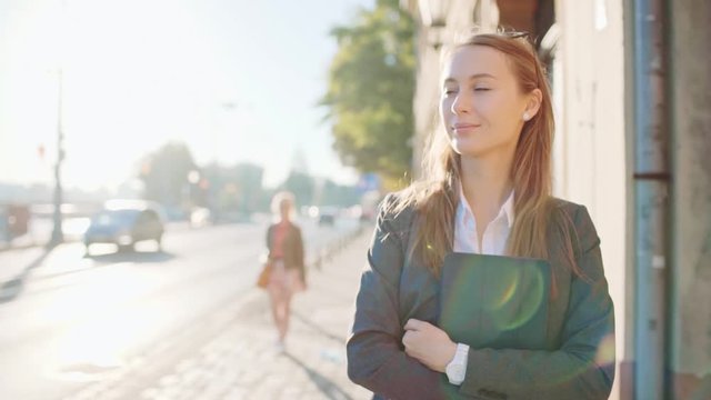 Young Businesswoman Going to Work in the Sunny Morning City. SLOW MOTION. STEADICAM Stabilized Shot. Attractive Professional Business Woman with Tablet rushing to a morning meeting. Lens Flare. 