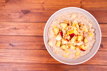 Obraz na płótnie Canvas Porridge with peach, apple, banana and walnut on a wooden table