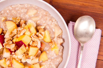 Porridge with peach, apple, banana and walnut on a wooden table