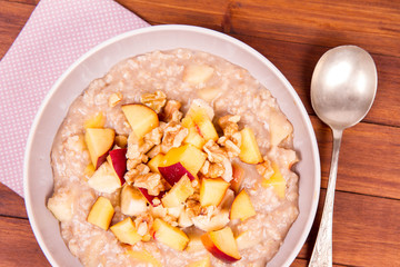 Porridge with peach, apple, banana and walnut on a wooden table
