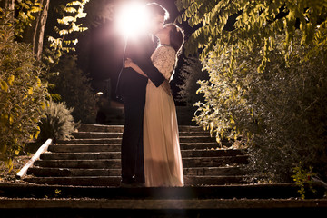 Bride and groom, outdoors, in romantic embrace