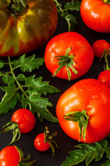 Fresh juicy tomatoes, cherry and leaves pattern and ornament on a black background with water drops and copy space flat top view and space for text