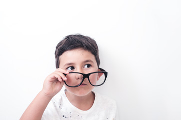 Serious boy looking from under large glasses. White background.