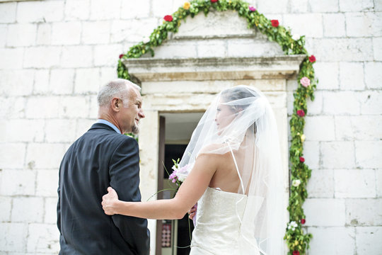 Father escorting bride to church, rear view