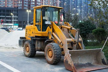 Old yellow bulldozer with caterpillar moving ground with scoop. Blue sky and white clouds in background
