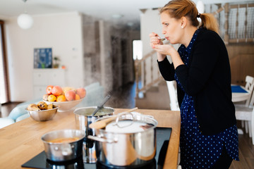 Housewife tasting food being made in kitchen