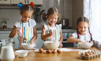 Photo sur Plexiglas Cuisinier happy sisters children girls bake cookies, knead dough, play with flour and laugh