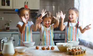 happy sisters children girls bake cookies, knead dough, play with flour and laugh
