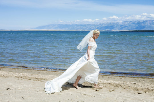 Bride in wedding dress walking on beach
