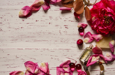 Wooden background framed with petals and pink accessories