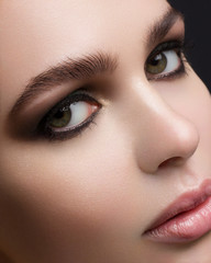 Obraz premium Largely a portrait of the beautiful girl with fashionable cosmetics on a face. Smoky eyes, big eyebrows and chubby natural lips. Cosmetology, beauty shop, cosmetics, injections