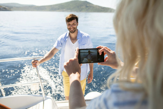 Young woman taking photo on sailboat, Adriatic Sea