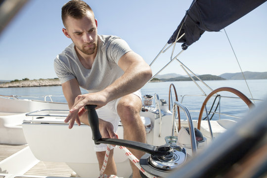Man turning on cable winch on sailboat, Adriatic Sea