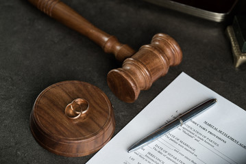 Image of wedding rings on wooden gavel at table in courtroom