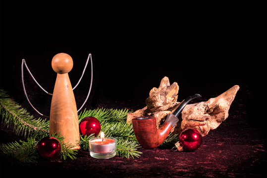 Holzengel  und Pfeife weihnachtlich geschmückt mit Tannen und Christbaumkugeln  