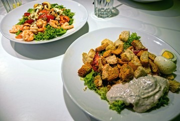 Экзотические салаты в белых тарелках на столе в ресторане