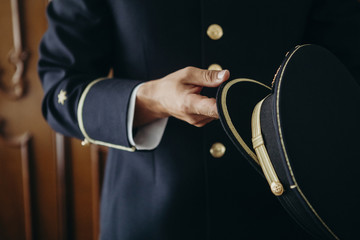 Man in uniform holding an official cap.