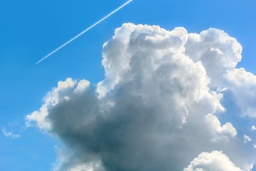 Blue sky with cumulus cloud and contrail, close-up