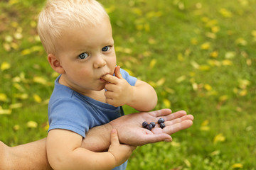 Cute one year toddler eating blueberry. Mother feeding her son with Blueberries