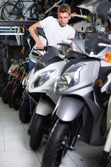 Portrait of male motorcyclist looking on the bike in the store
