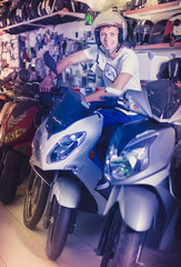 Obraz na płótnie Canvas Portrait of glad male in helmet on motorbike in the store